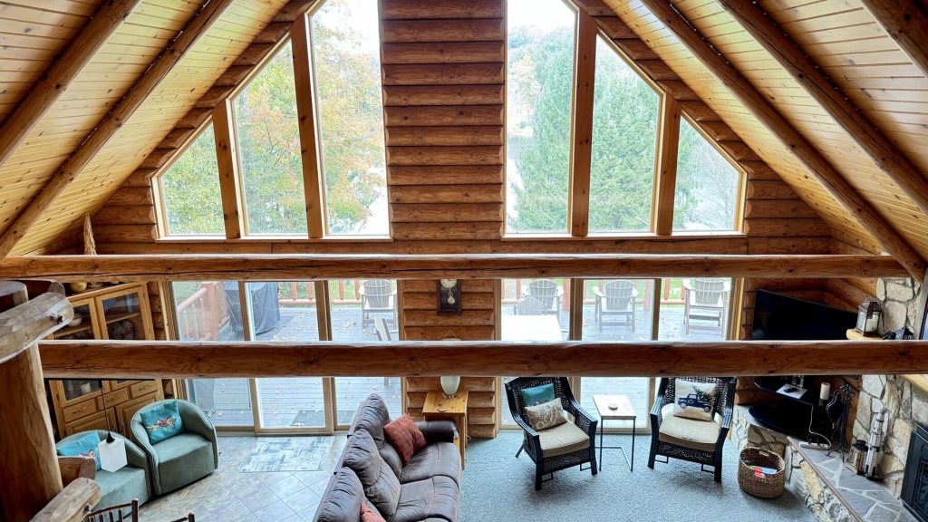 View from the loft down into the great room with windows and log beams