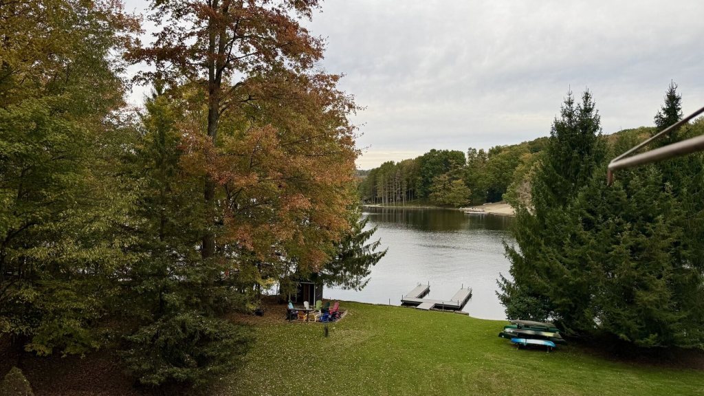 The lake seen between orange fall trees and tall pines