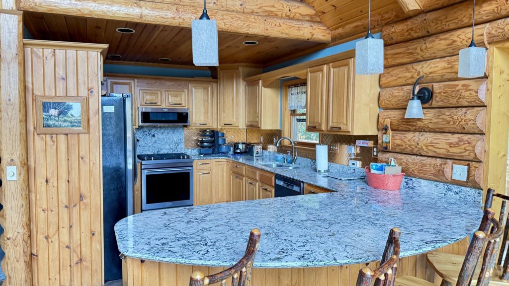 Kitchen with pine cabinets, stainless appliances and a curved granite island