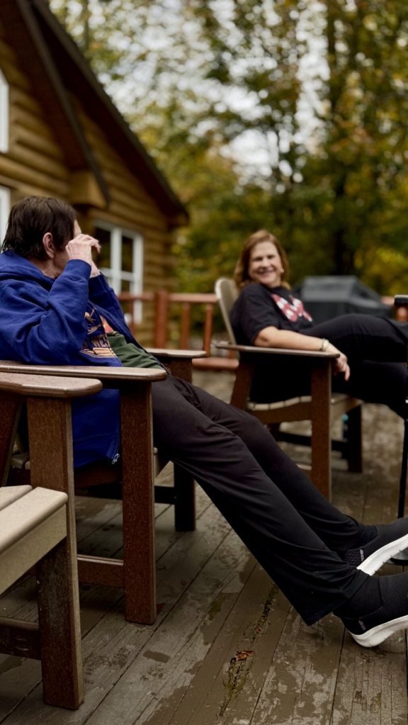 Family relaxing in Adirondack chairs on the cabin deck