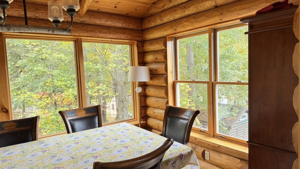Dining table by large windows looking out on fall trees
