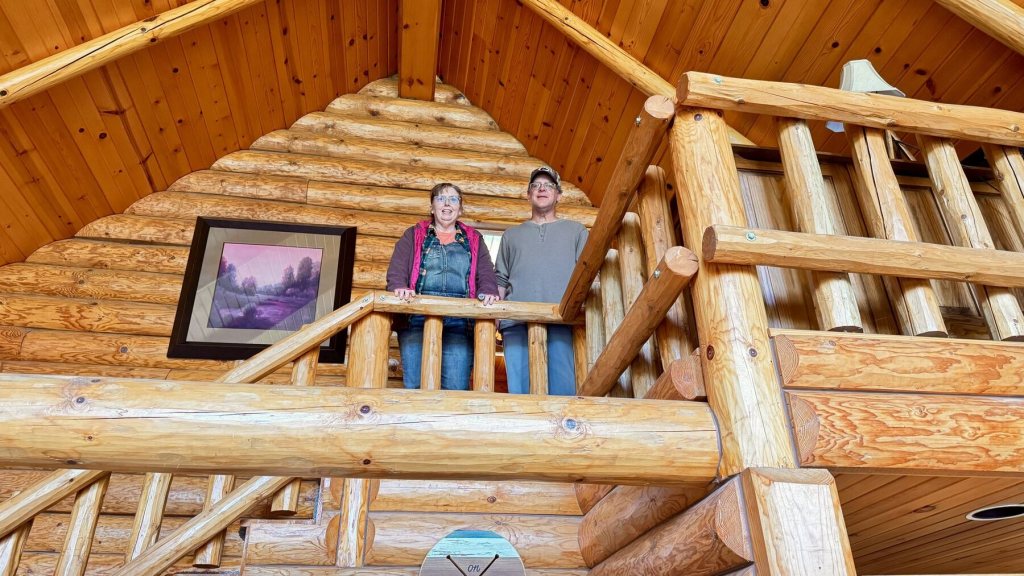 Corilee and Grant looking down from the log loft inside the cabin