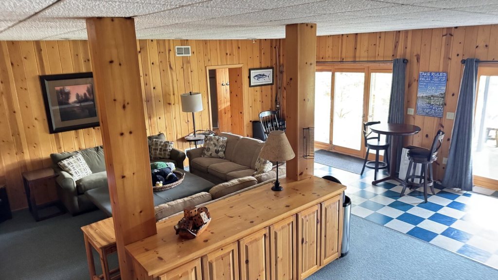 Family room with a sofa, log posts and a small bar on a checkerboard floor