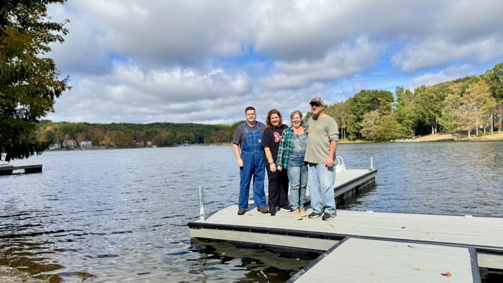 Four family members standing on the dock at Treasure Lake under a partly cloudy sky