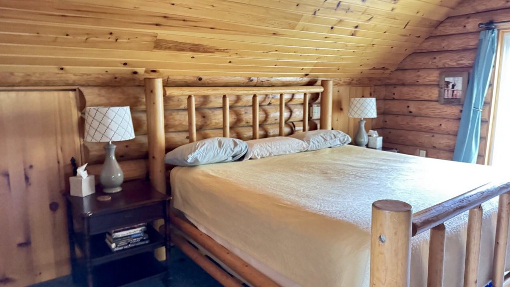 Bedroom with a log bed frame and pine walls