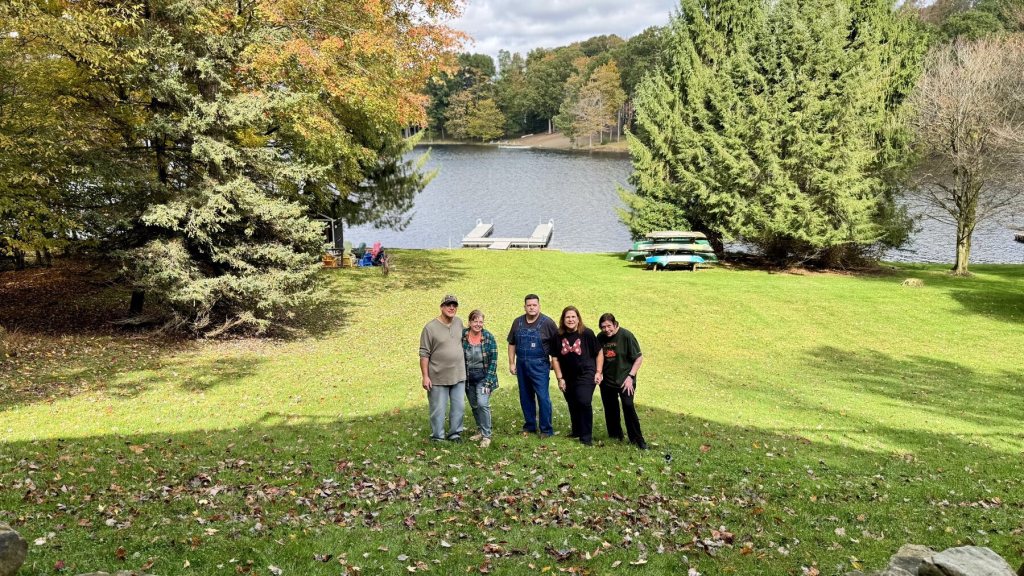 Five family members posing together on the lawn with Treasure Lake and tall pines behind them