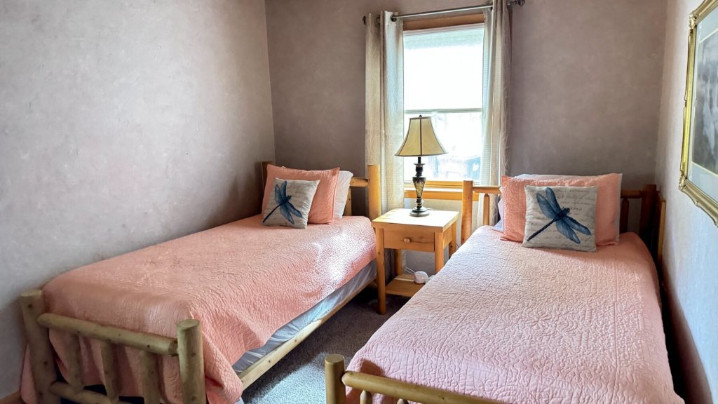 Bedroom with two twin log beds and dragonfly pillows
