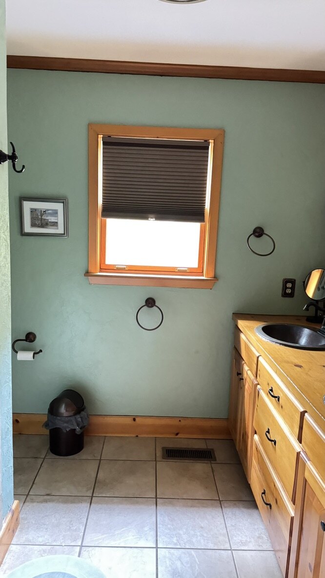 Bathroom with green walls, a pine vanity and a copper sink