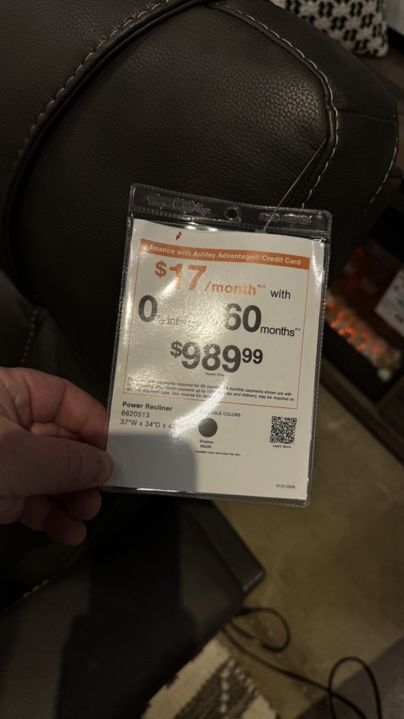 Price tag on a dark leather power recliner at Ashley showing $989.99 or $17 a month for 60 months