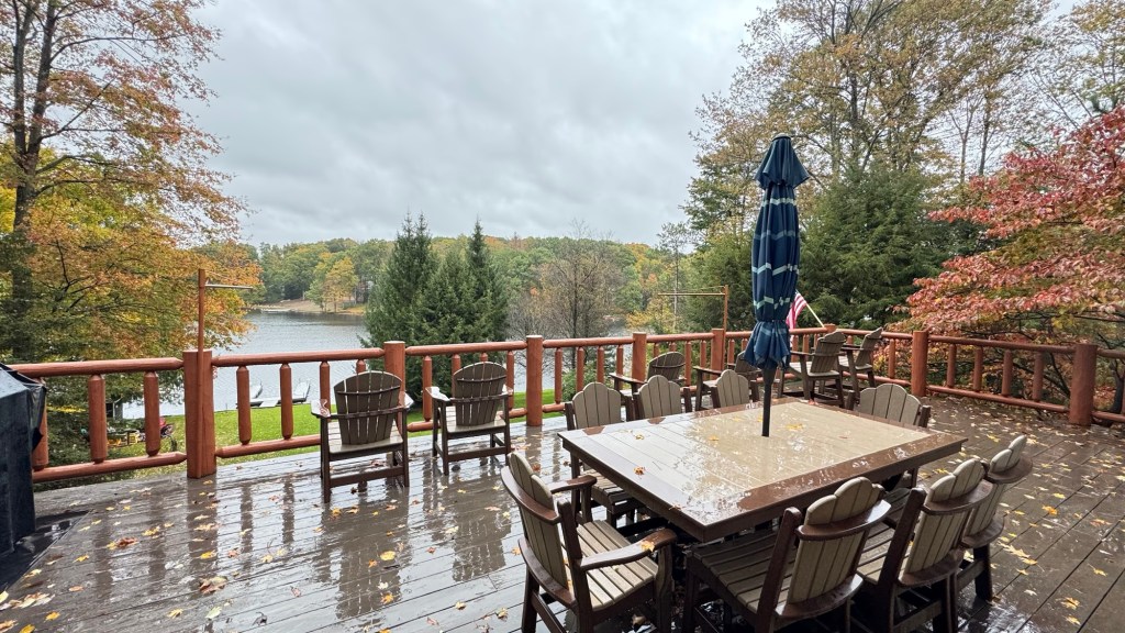 Rain-soaked cabin deck with table and closed umbrella overlooking Treasure Lake