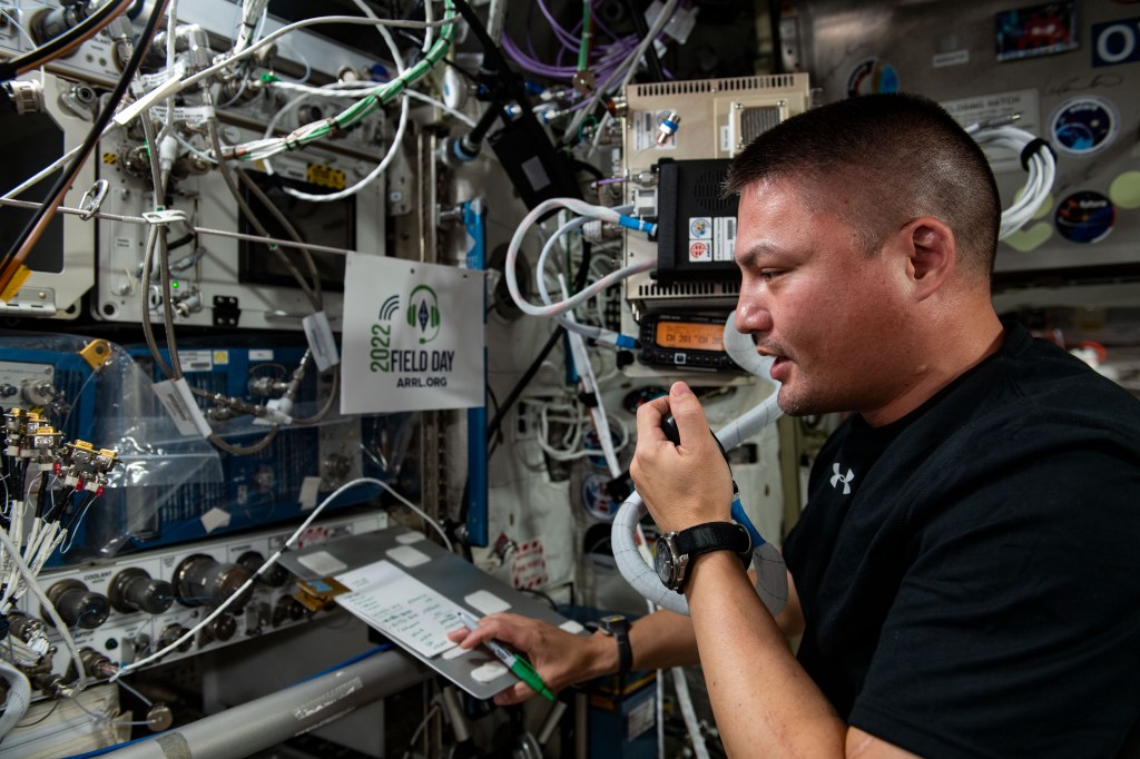 NASA astronaut Kjell Lindgren speaking into a microphone at the ham radio station aboard the International Space Station