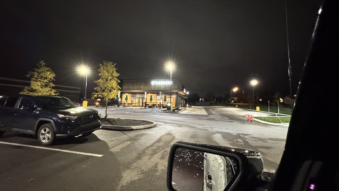 A Starbucks lit up in the dark on a wet early morning